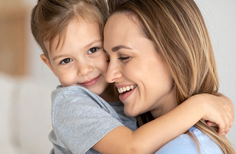 Woman and child embracing, smiling; indoors.