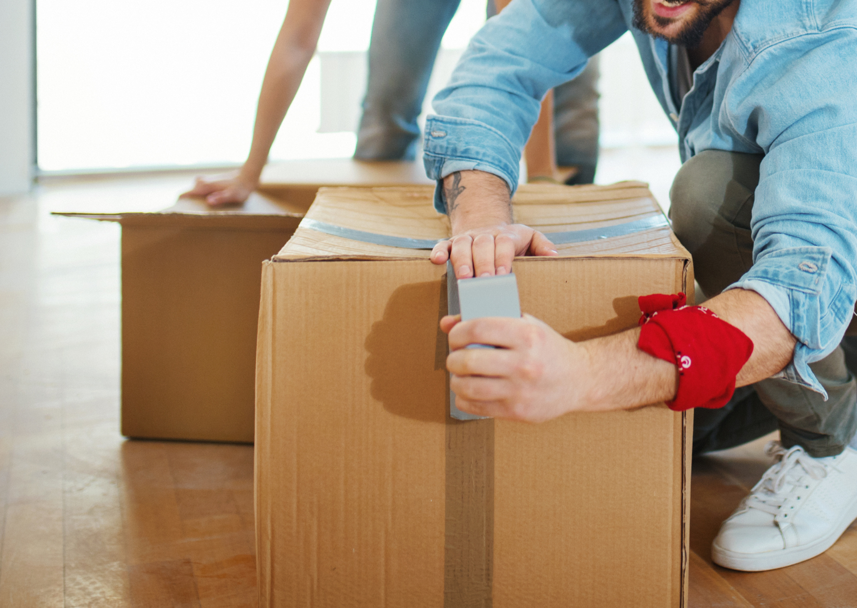 A man is wrapping a cardboard box with duct tape.