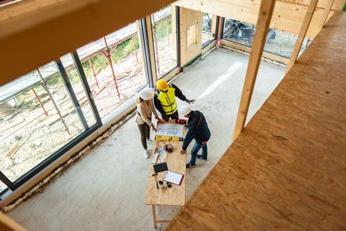 A Group Of Construction Workers Are Looking At A Blueprint At A Construction Site - West Salem, WI - Coulee Construction and Concrete LLC