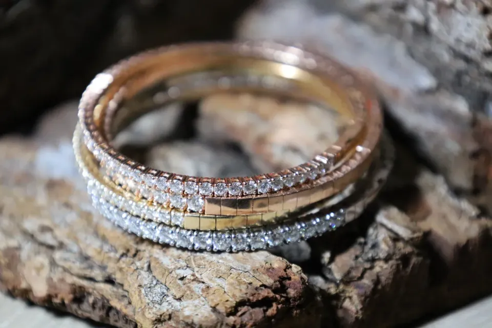 Stacked gold and silver rings on rustic wood, with a small diamond accent