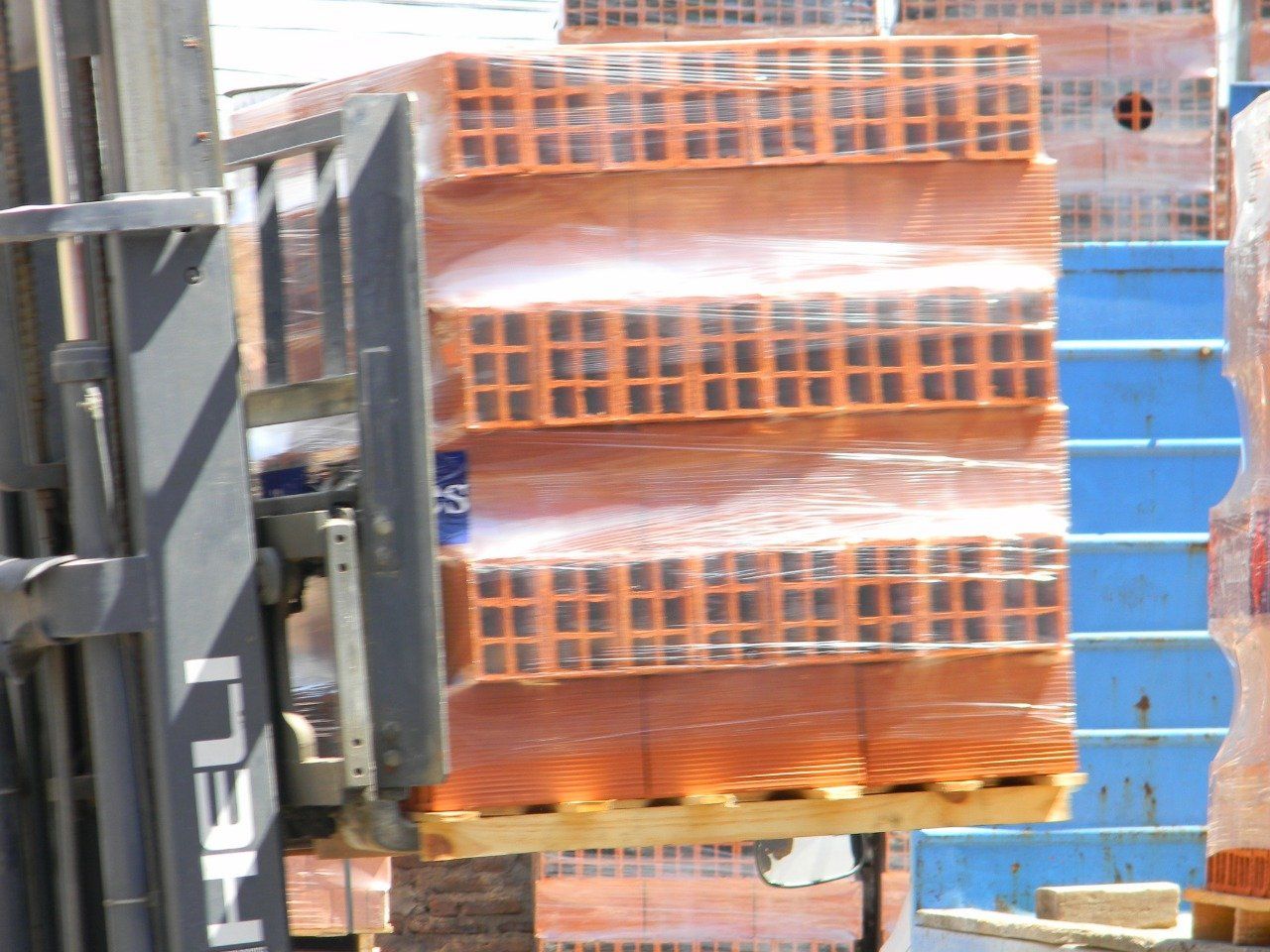 Una carretilla elevadora transporta una pila de ladrillos sobre un palé.