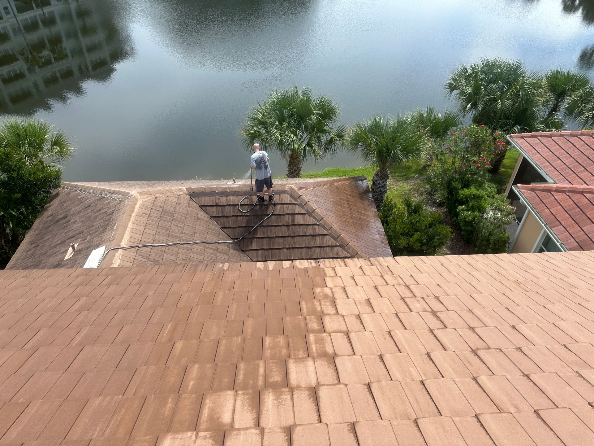 Technician in Palm Coast soft-washing a tile roof to safely clear black algae streaks and dirt