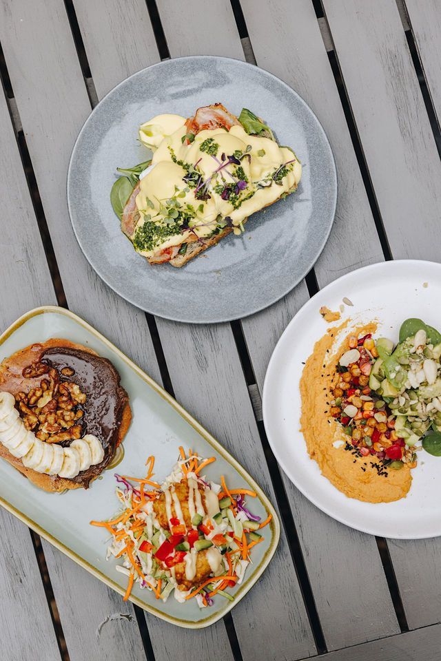 Three plates of food are sitting on a wooden table.