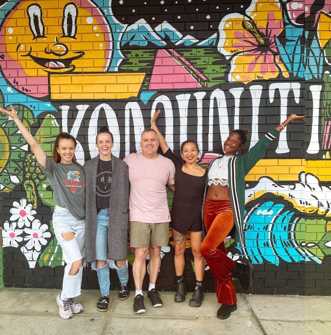A group of people standing in front of a mural that says ' hawaii ' on it