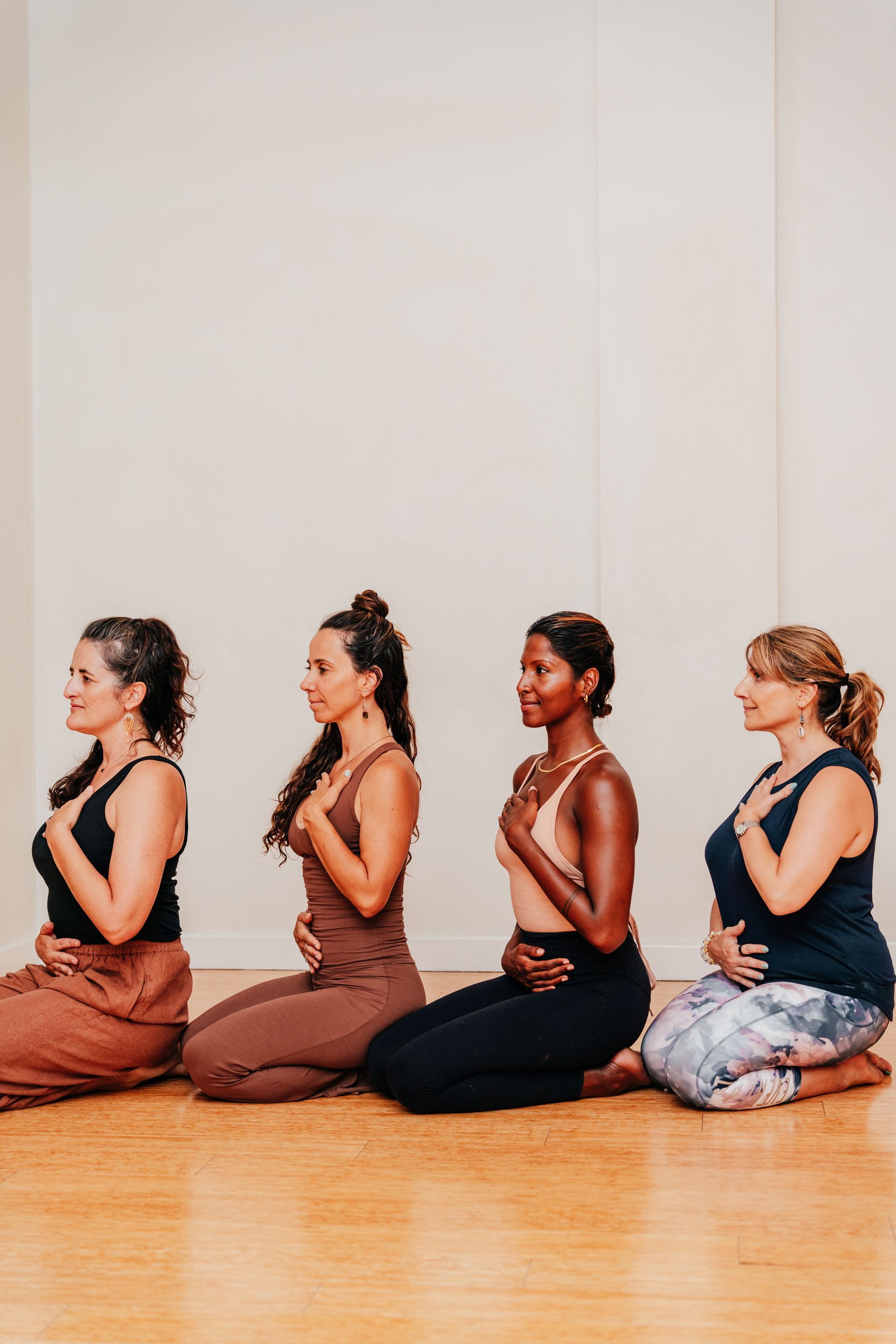 A group of women are kneeling on the floor in a yoga pose.