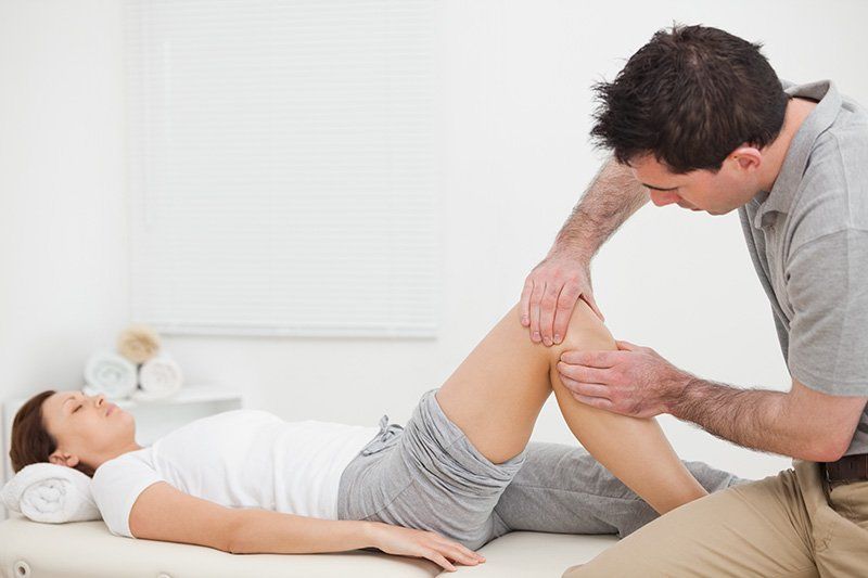 Physiotherapist massaging the knee of woman