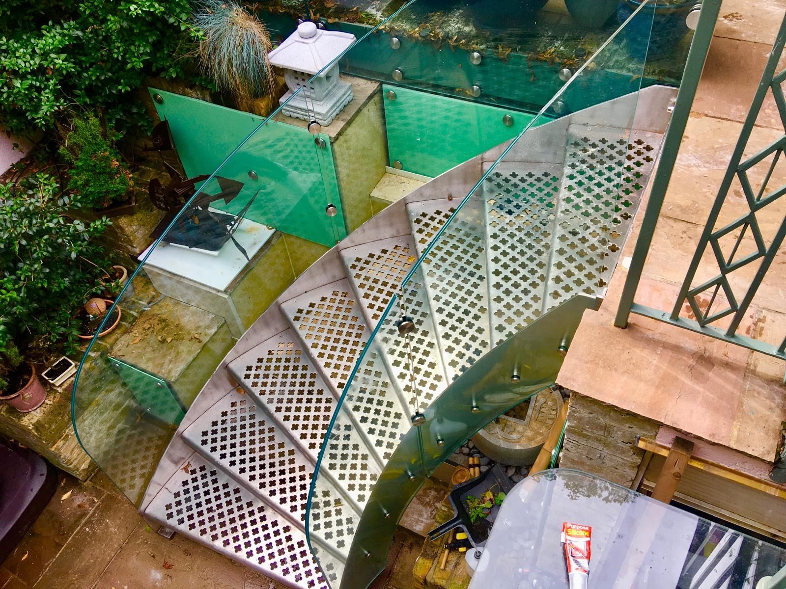 Helical external staircase with perforated steel treads and glass balustrade