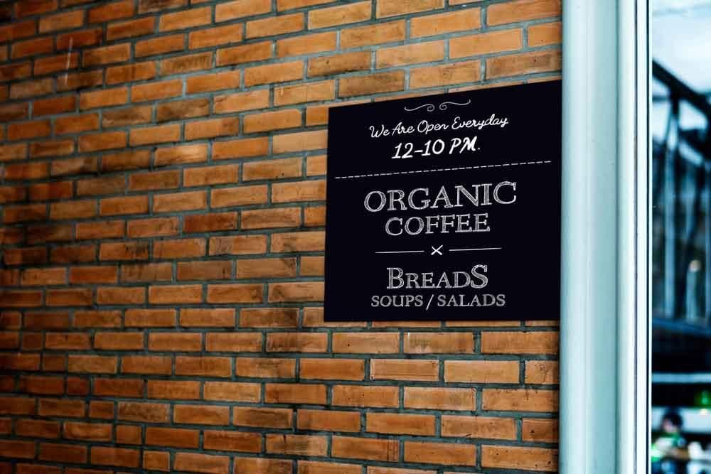 A Sign on A Brick Wall Says Organic Coffee Breads Soups Salads — Solarmaster in East Brisbane, QLD