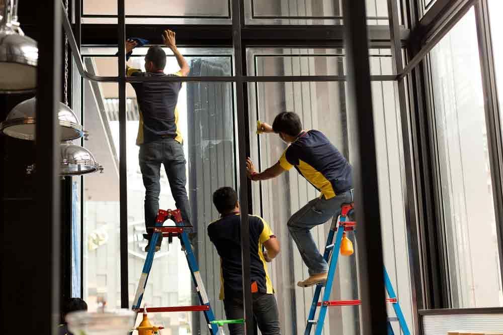 Three Men Are Standing on Ladders Cleaning a Window — Solarmaster in Brisbane, QLD