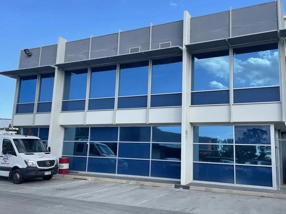 A White Van Is Parked in Front of A Building with Blue Windows — Solarmaster in Murarrie, QLD