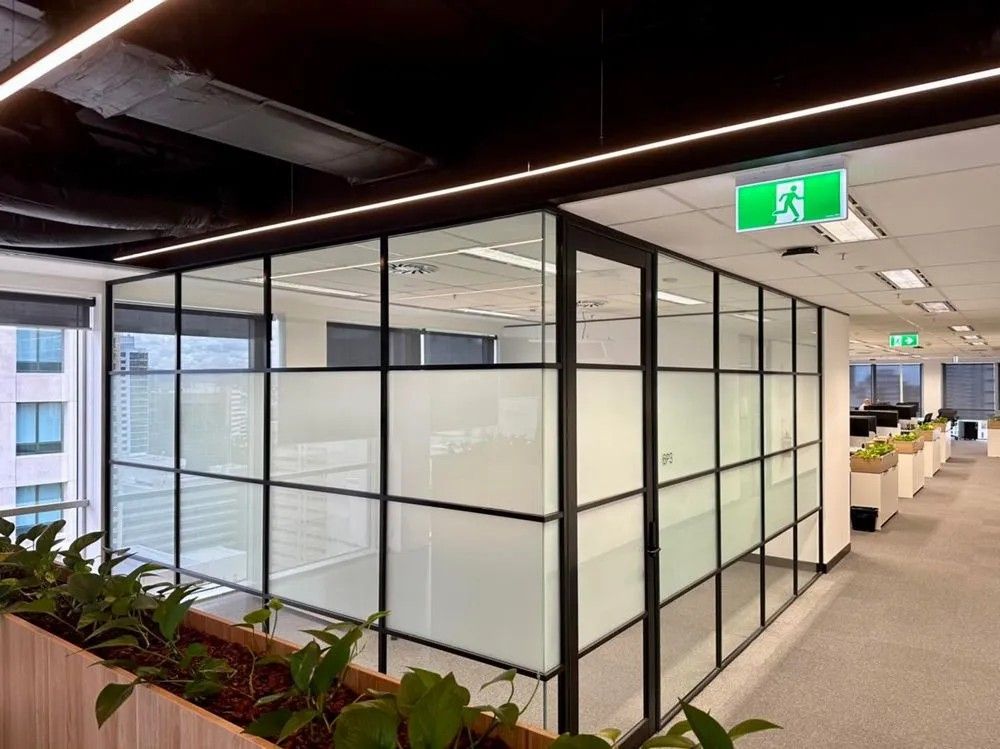 A Hallway in An Office Building with A Green Exit Sign Hanging from The Ceiling — Solarmaster in Murarrie, QLD
