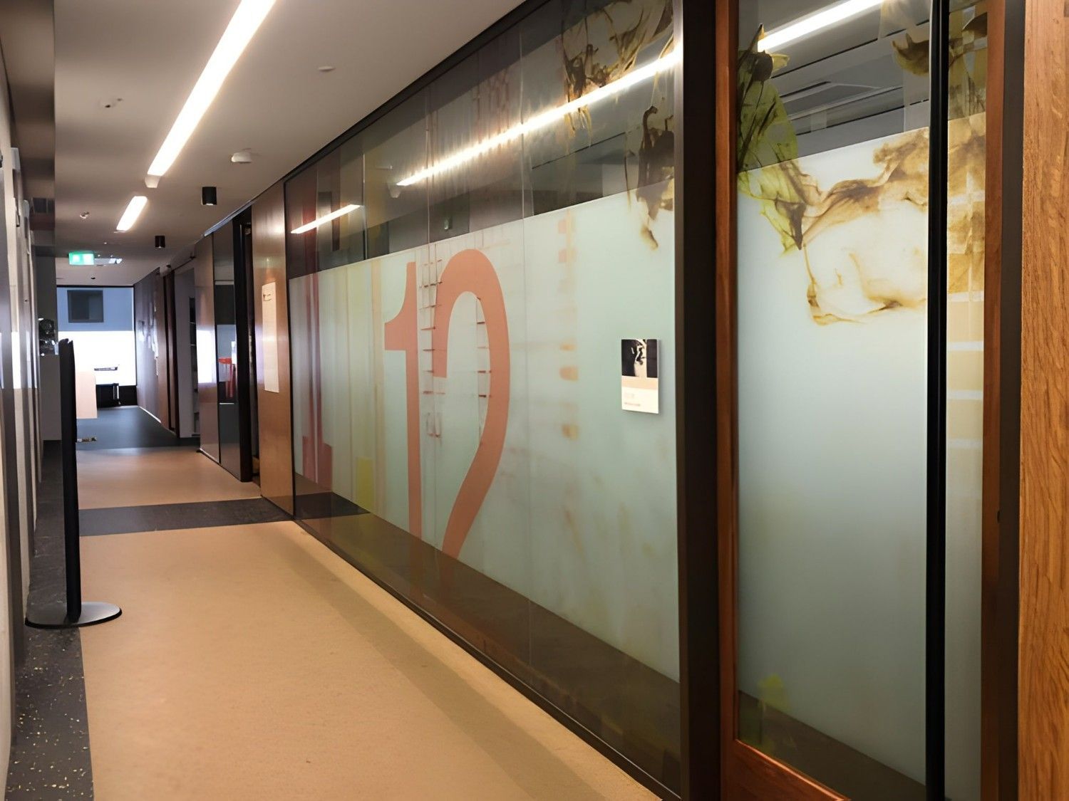 Long Hallway With Frosted Glass Windows, Number 12 Visible. Light Wood Frames, Recessed Lighting, And Beige Floor