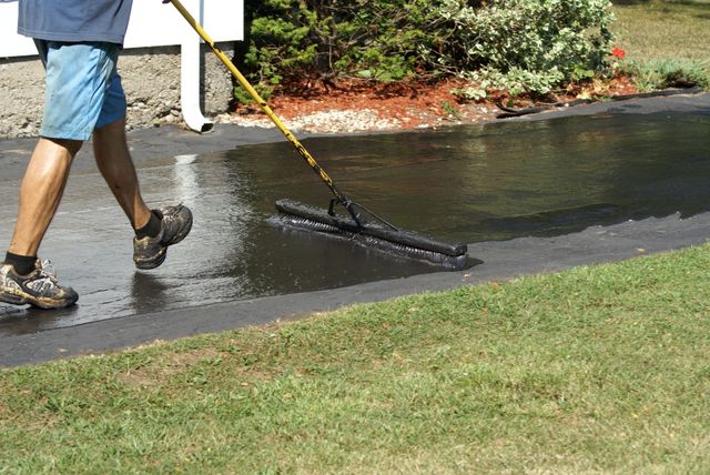 A worker applies sealant to a new driveway