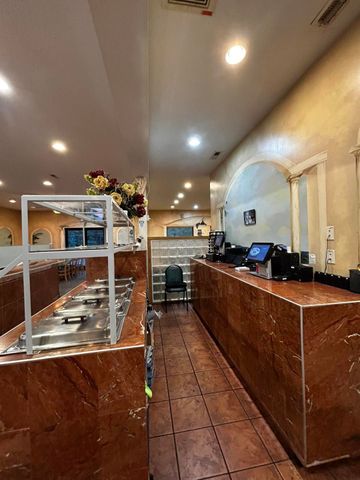 Restaurant interior: marble counter, food display, tile floor. Warm lighting. Flowers on counter.