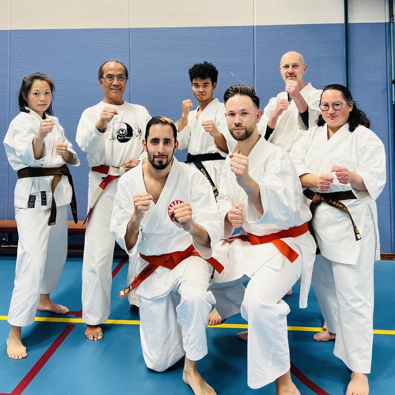 Volwassen karateka's in gevechtshouding met de twee examen kandidaten voorop.