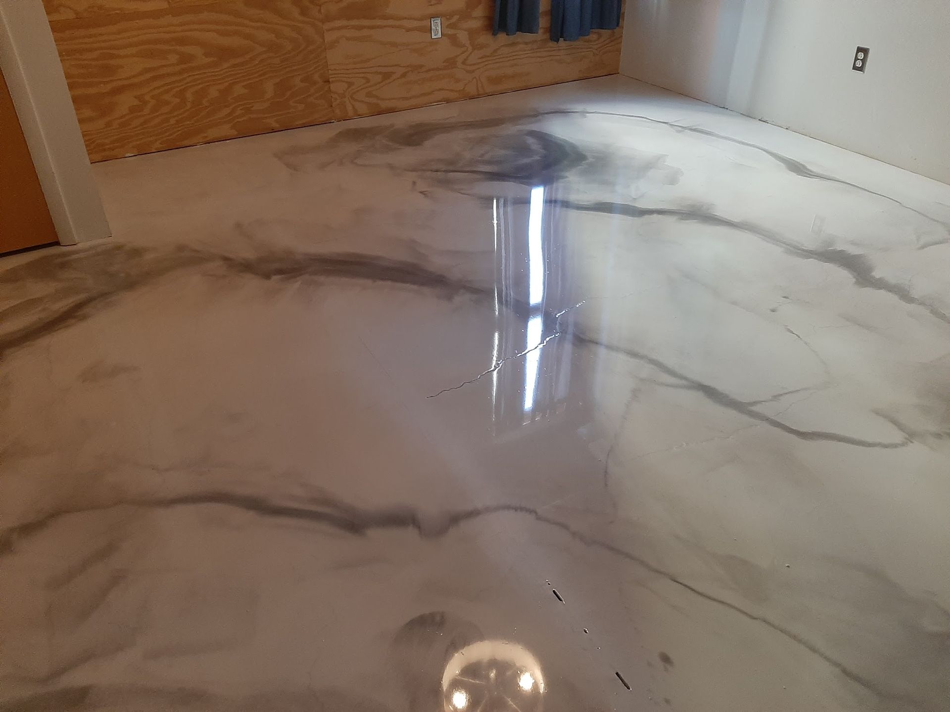 Metallic epoxy flooring with gray marbling effect. Reflective, light-colored room.