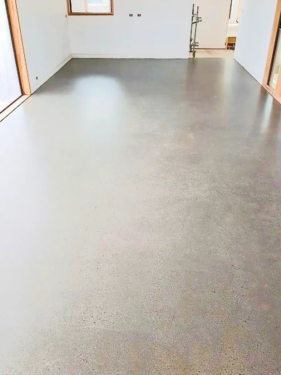 Polished concrete floor in an empty room with white walls and wooden door frames.
