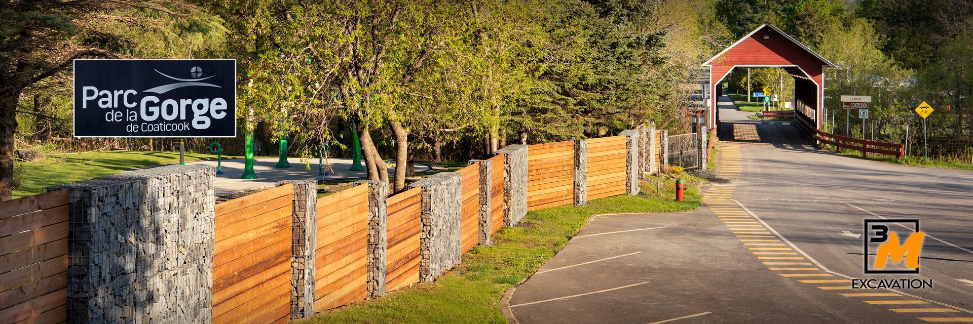 Un panneau indiquant le Parc du Gorge à côté d'une clôture en bois et d'un pont couvert sur une route.