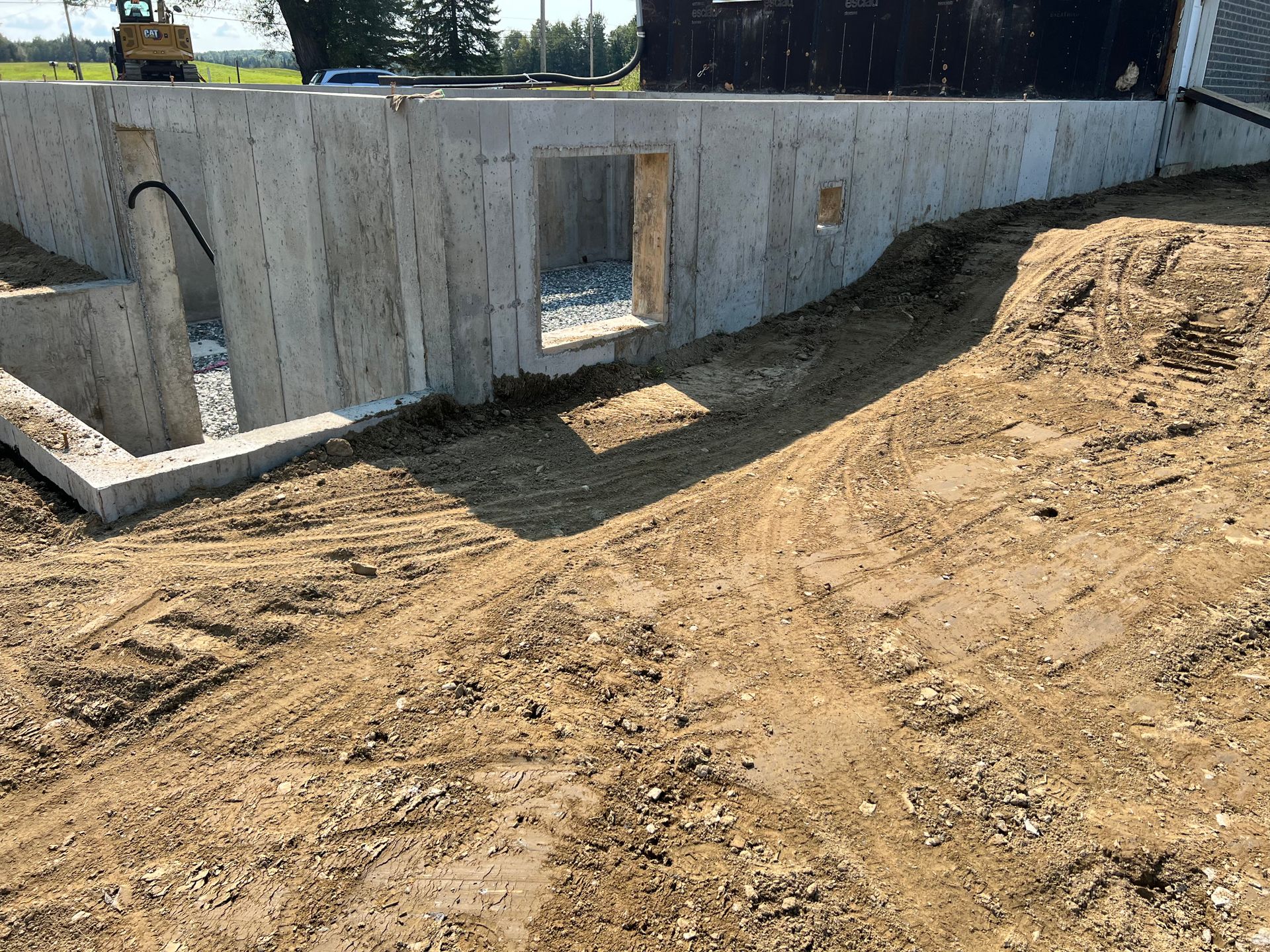Un mur de béton est en cours de construction à côté d'un terrain en terre.