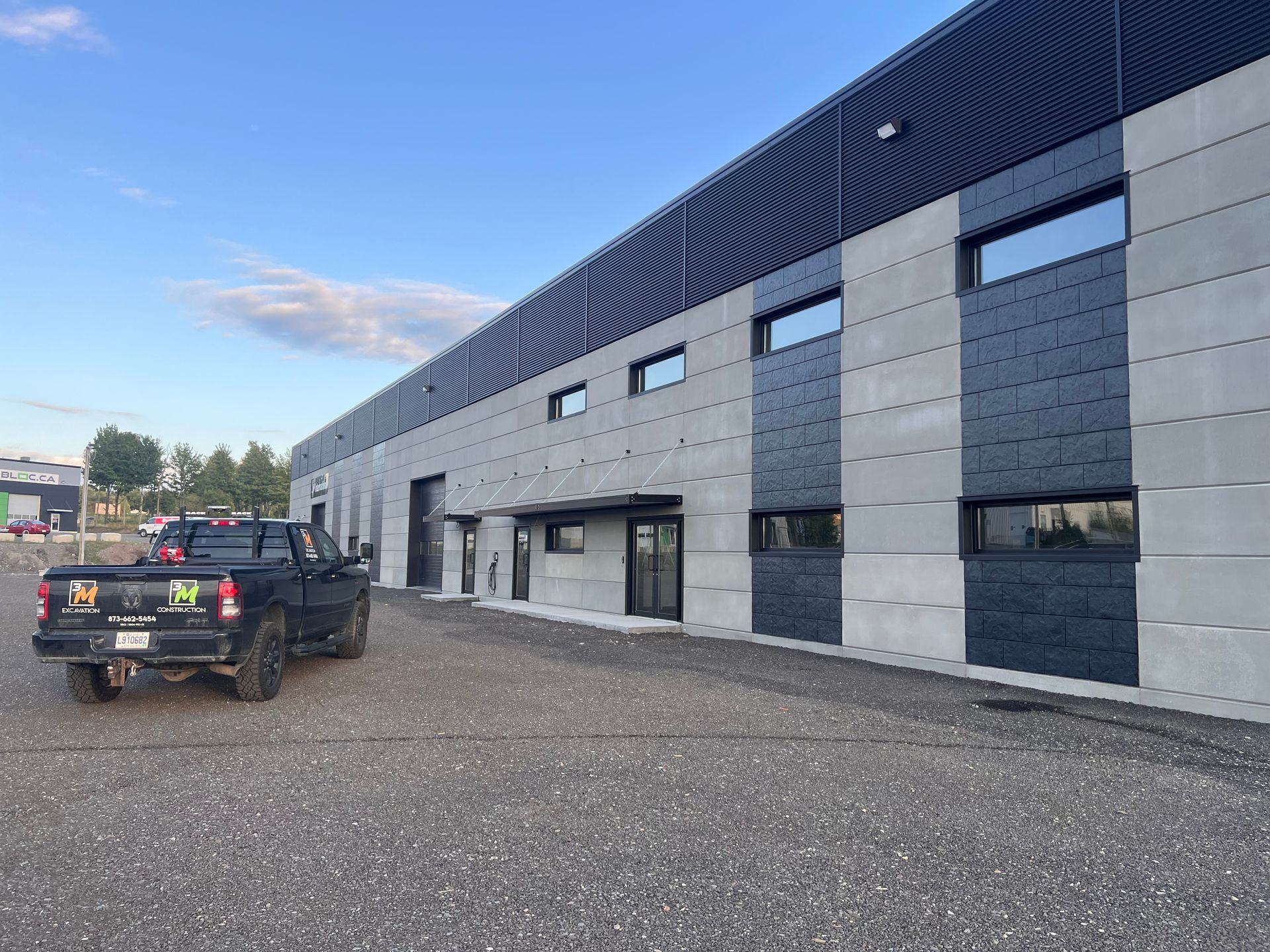 Un camion noir est garé devant un grand bâtiment.
