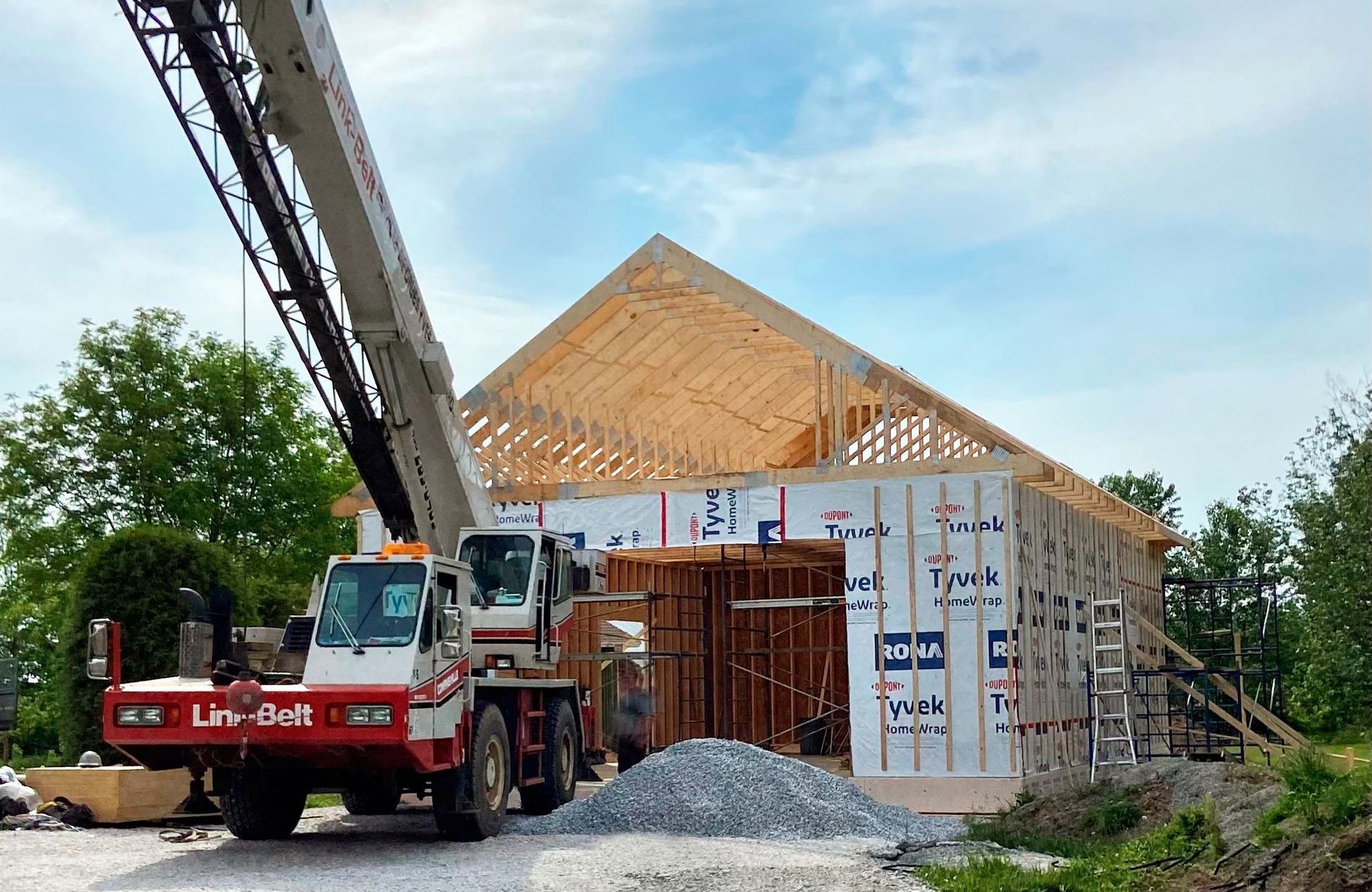 Une grue est assise devant un bâtiment en construction.
