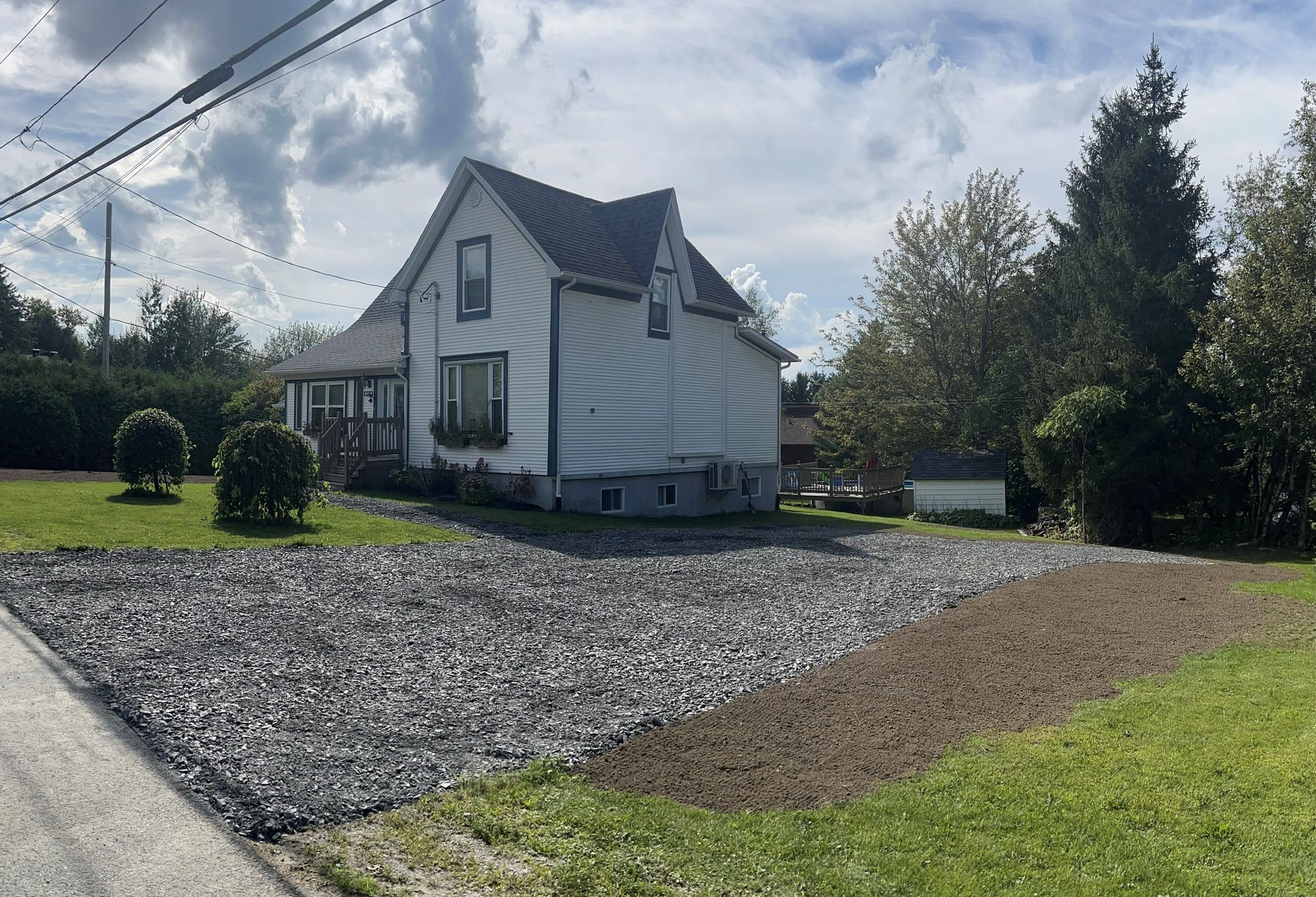 Une maison blanche avec une allée de gravier devant elle