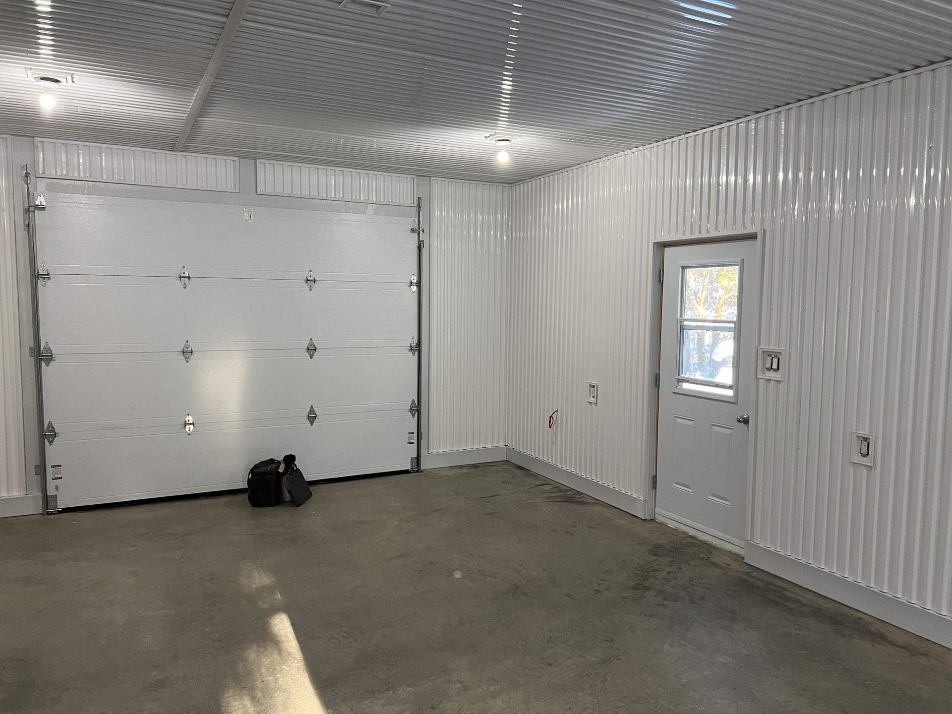 Un garage vide avec une porte de garage blanche et une fenêtre.