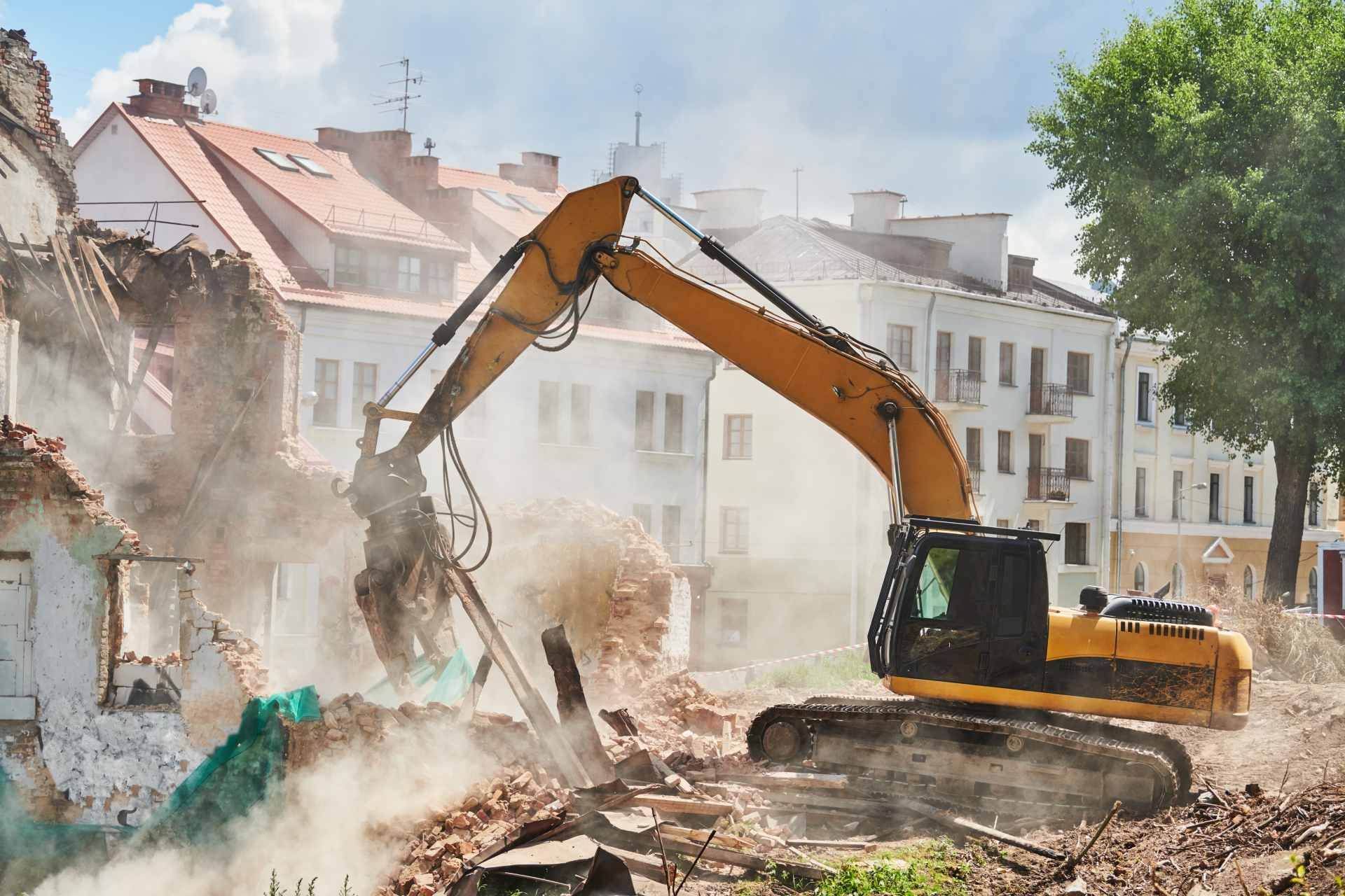 Excavator demolishing a building amid dust and rubble in a city street