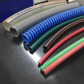 Mangueras industriales de varios colores, incluidos estilos corrugados y lisos, sobre una superficie oscura.