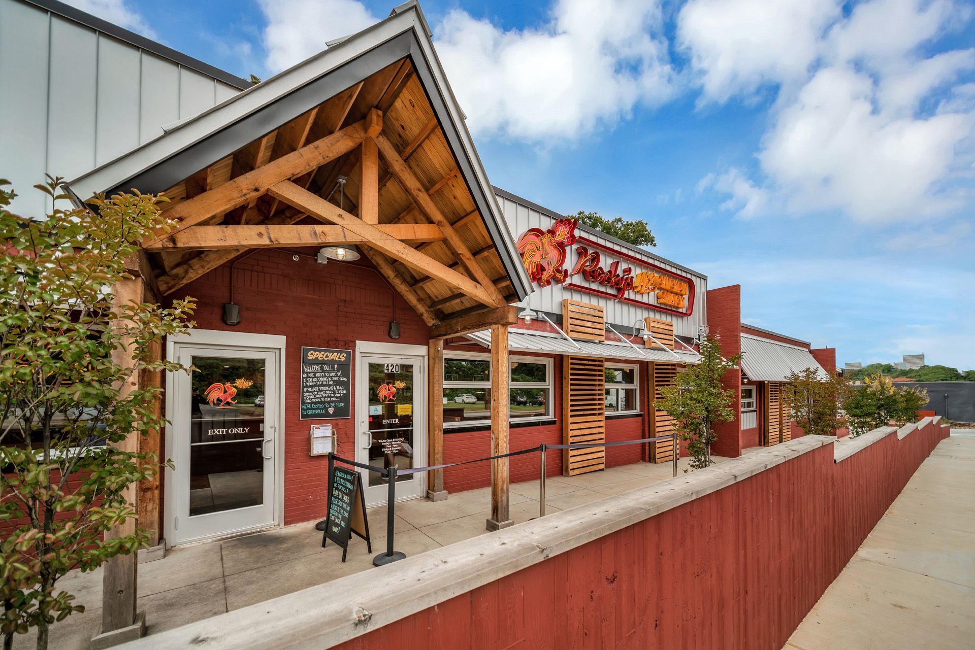 The outside of a restaurant with a wooden roof and a red fence.