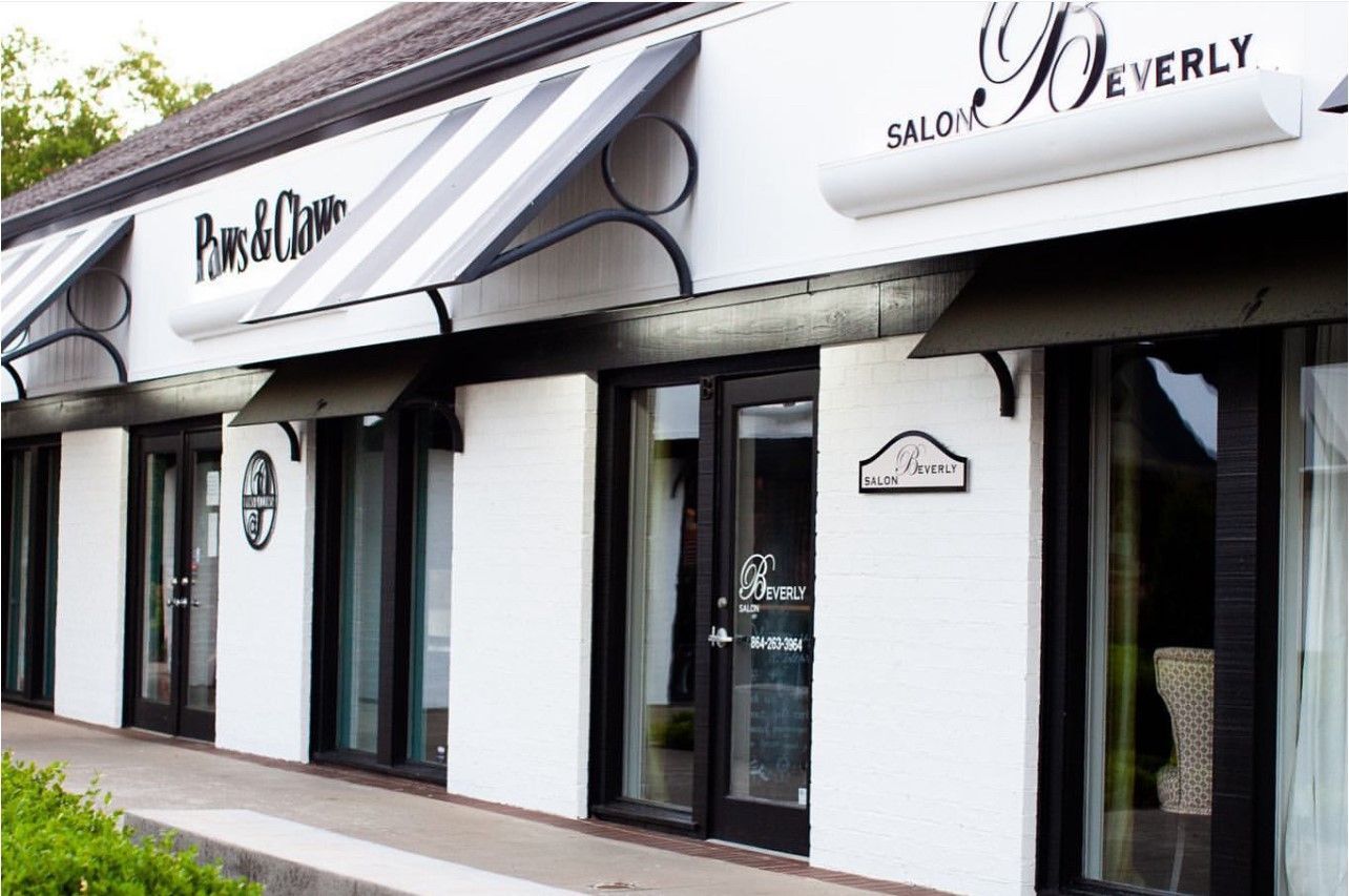 A white building with a black awning that says beverly salon