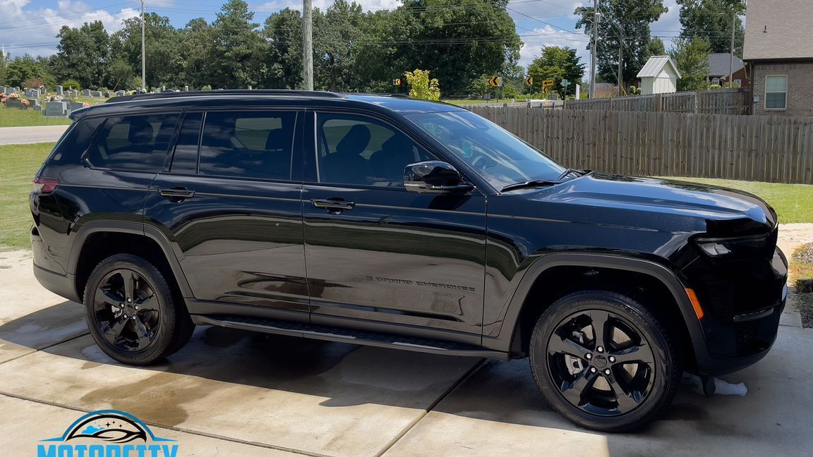 A black jeep grand cherokee is parked in a driveway.