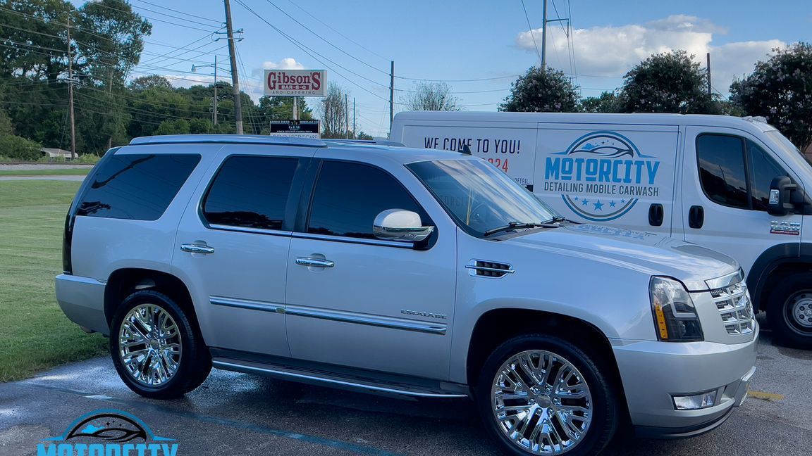 A silver suv is parked next to a white van.