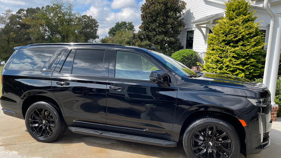 A black suv is parked in front of a house.