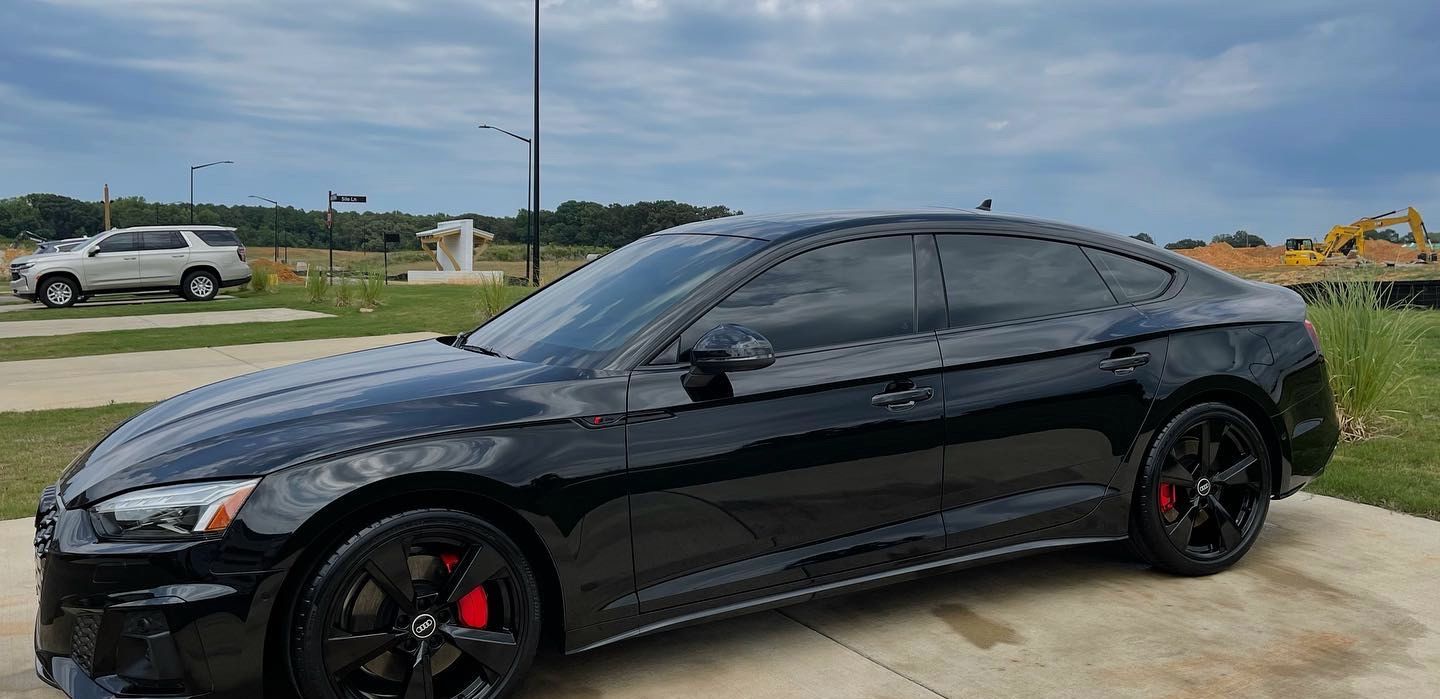 A black audi a5 is parked on the side of the road.