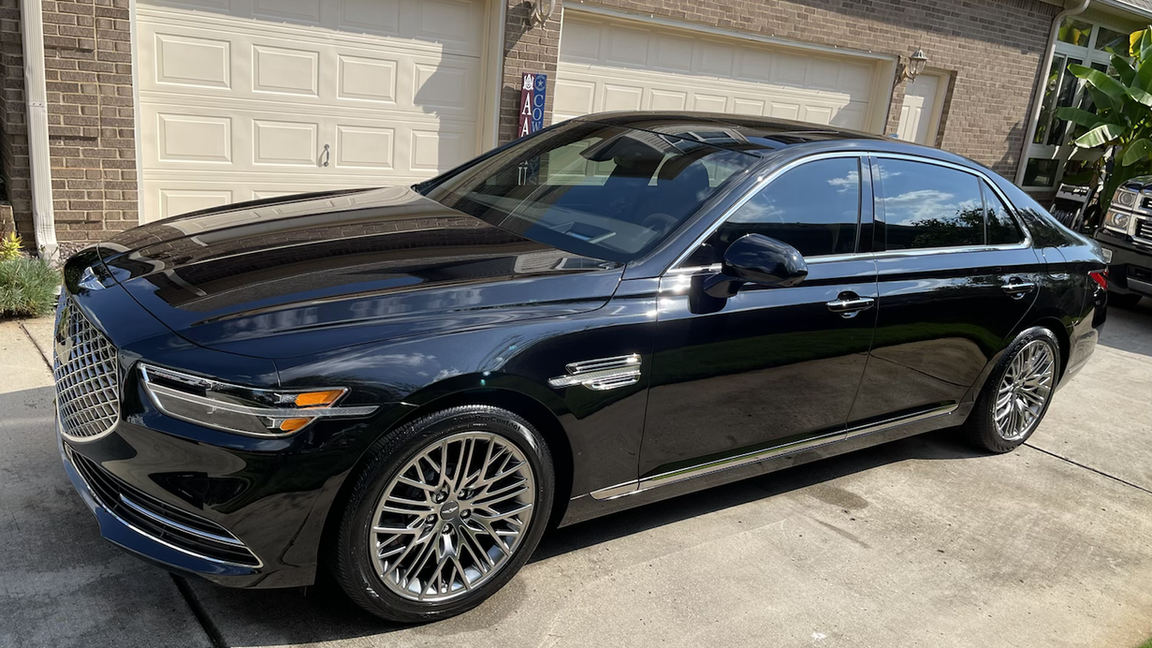 A black car is parked in front of a garage door.