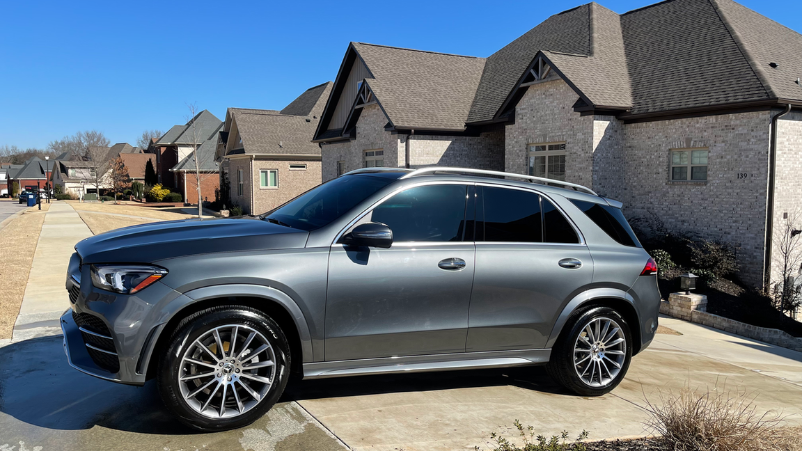 A gray suv is parked in a driveway in front of a house.