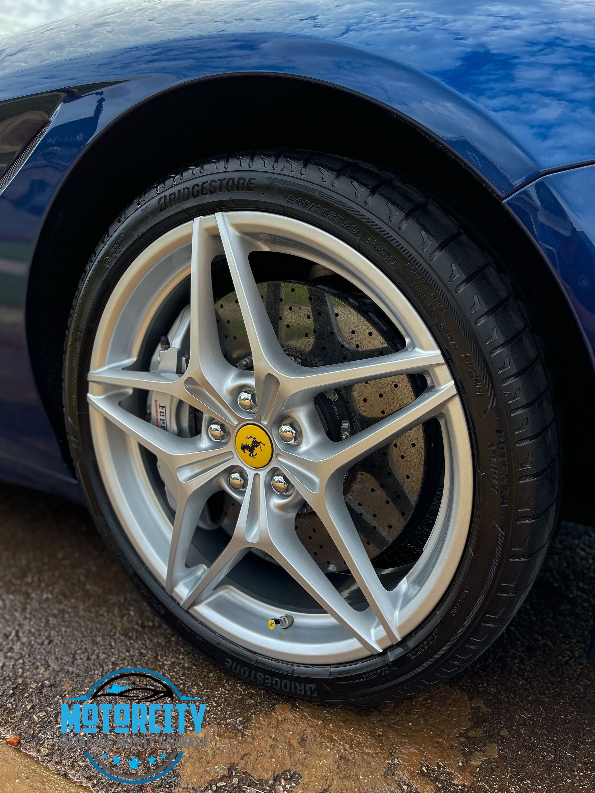 A close up of a ferrari wheel on a blue car.