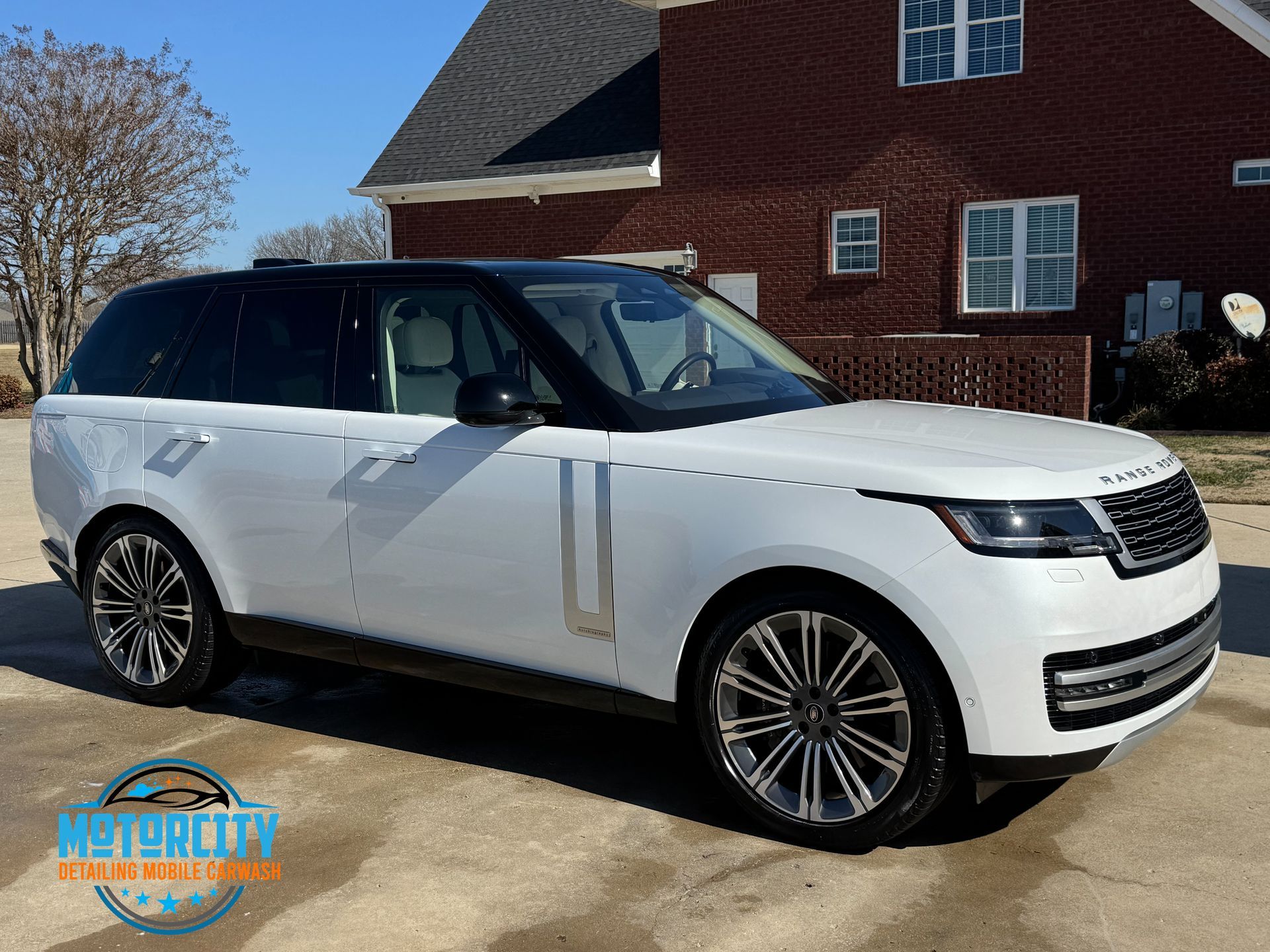 A white range rover is parked in front of a brick house.