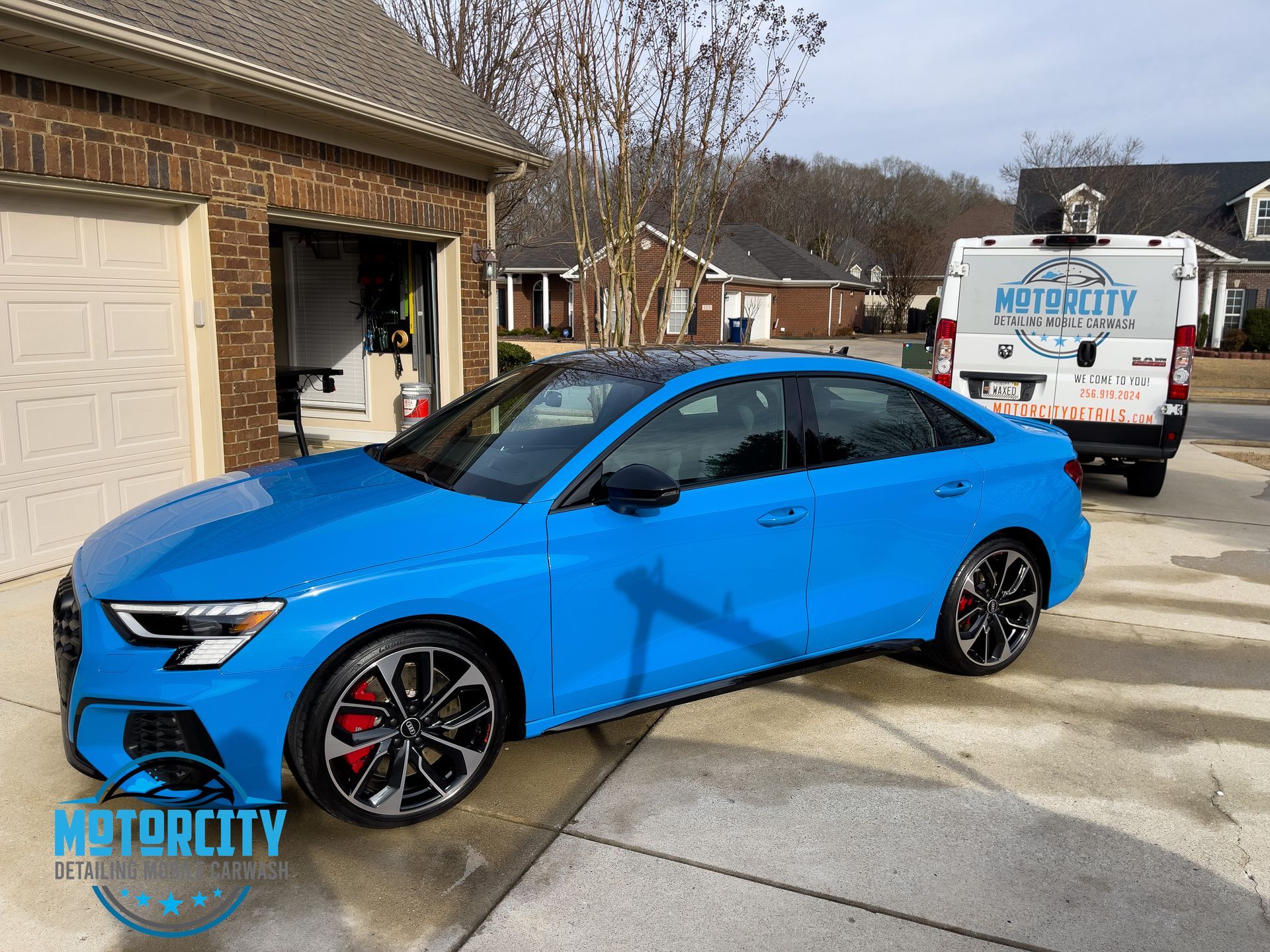 A blue car is parked in front of a garage.