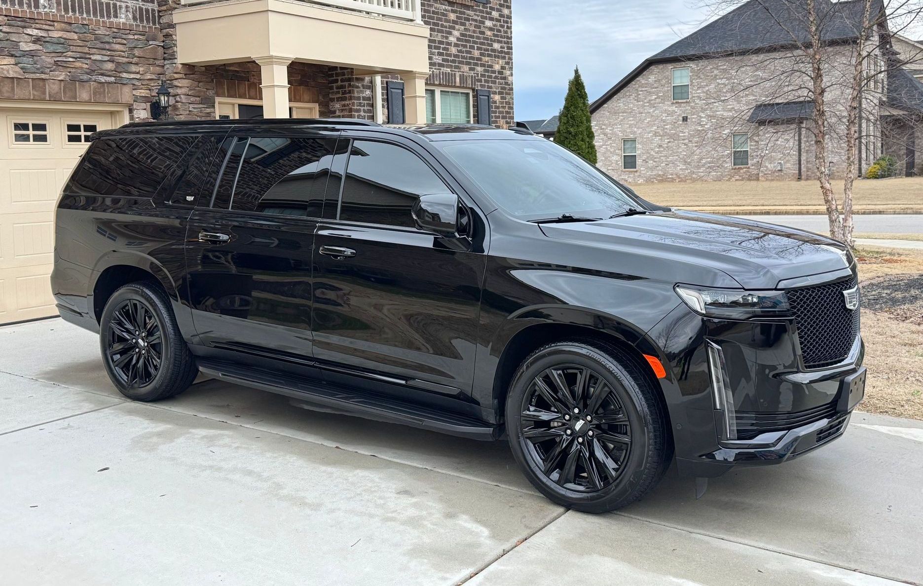 A black suv is parked in front of a large house.