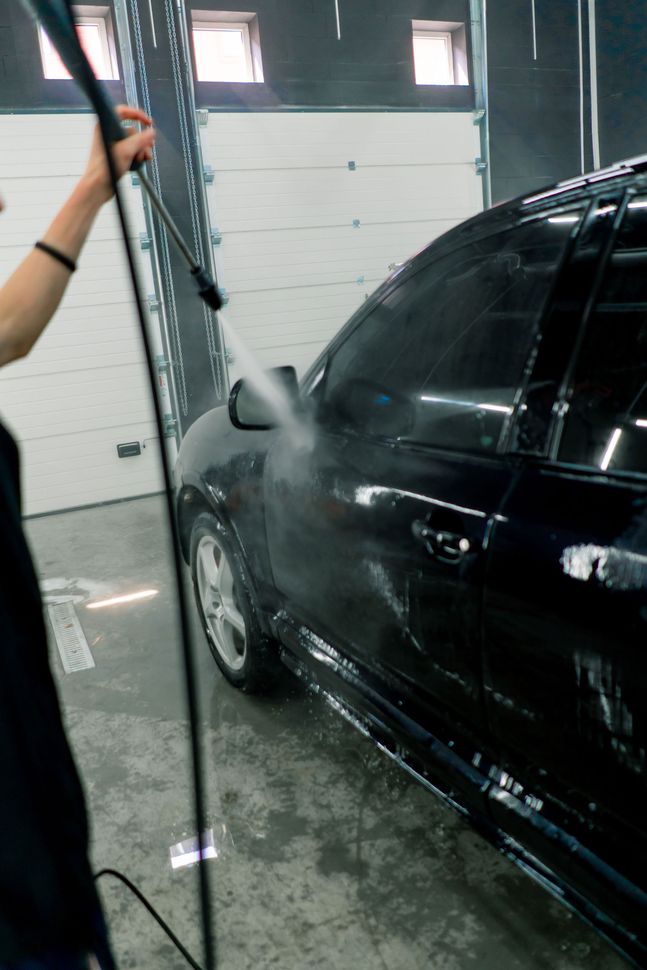 A man is working on the front of a car with the hood open.