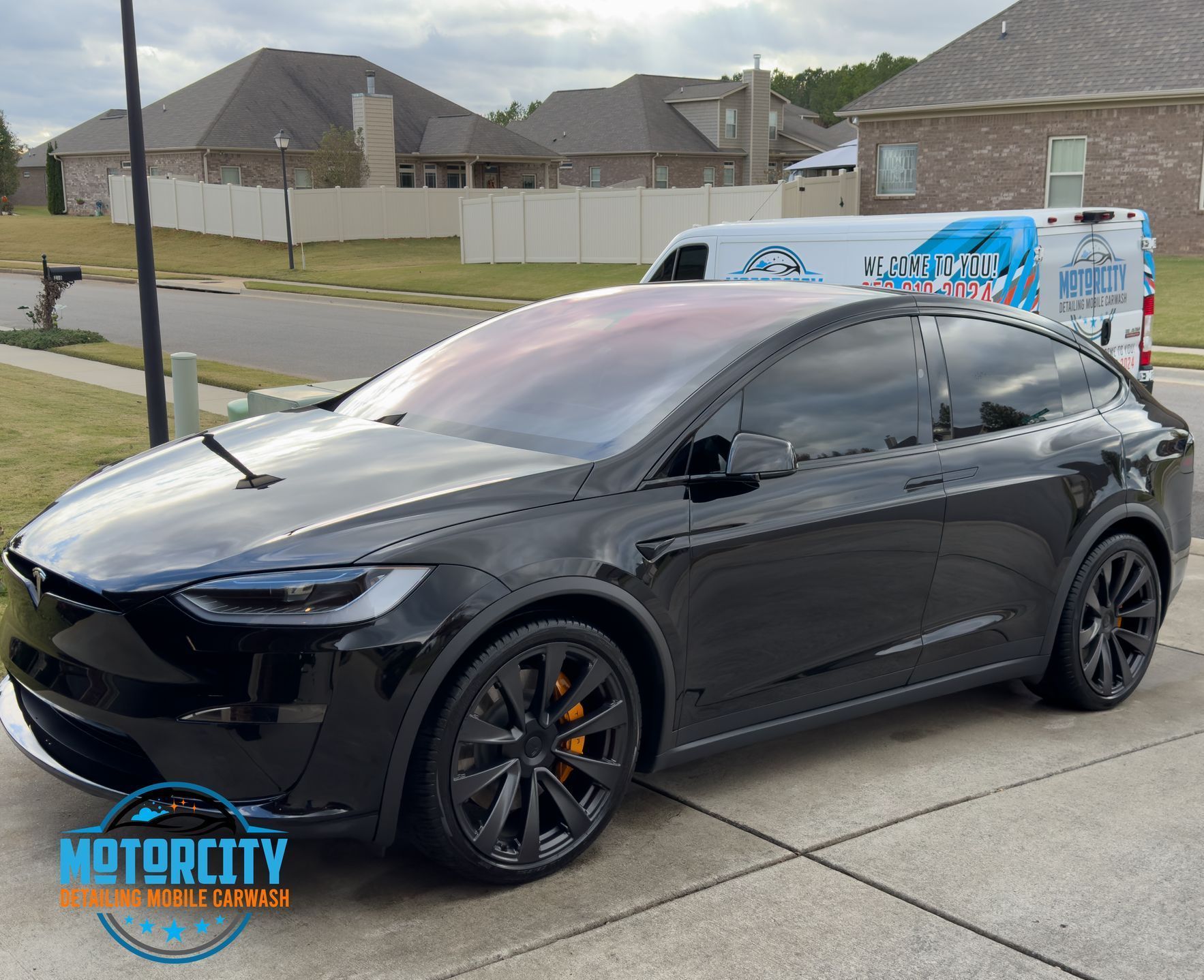 A gray dodge charger is parked in a driveway in front of a house.