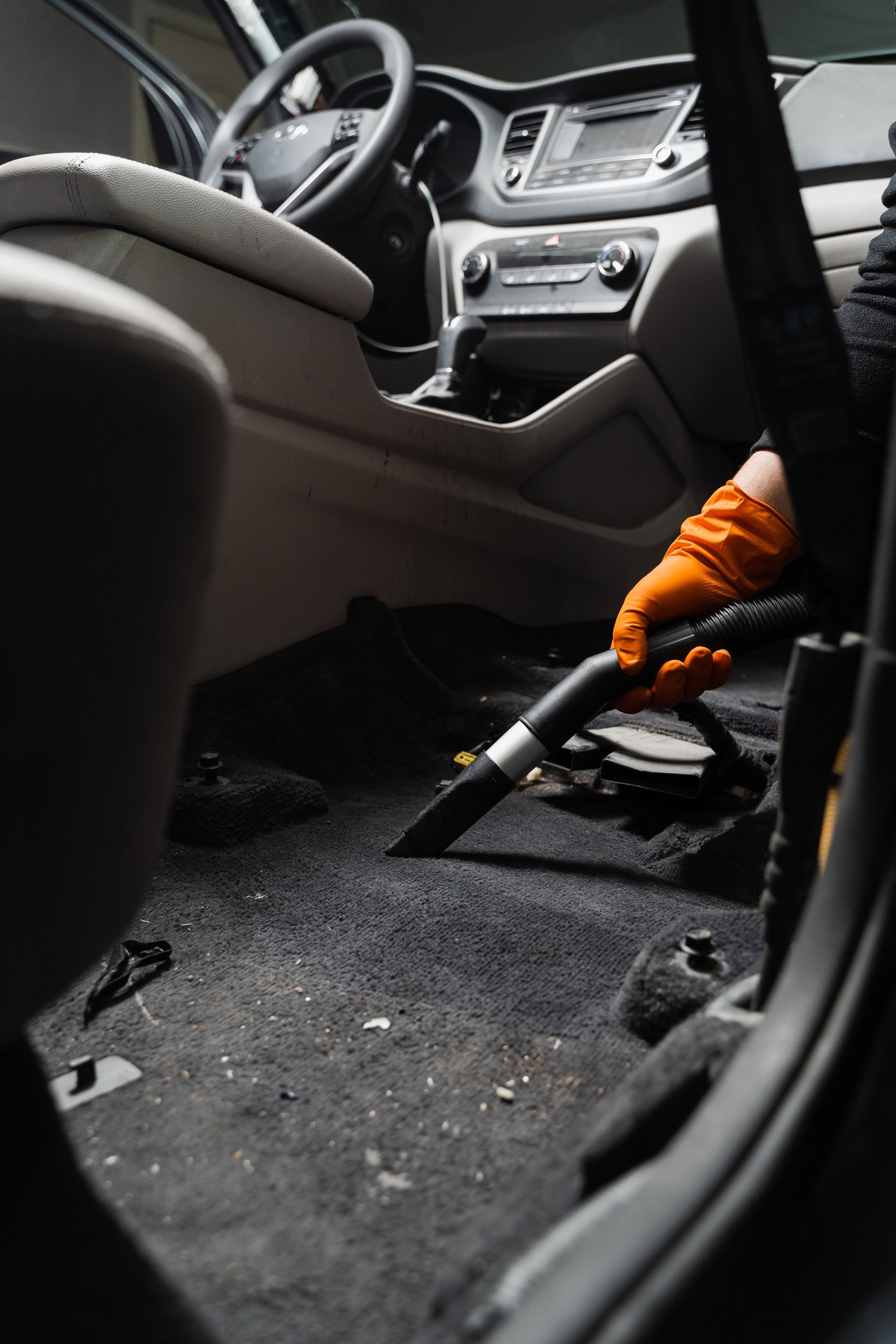 A person is cleaning the interior of a car with a vacuum cleaner.