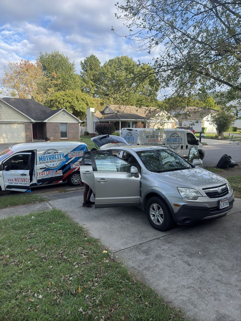 A car is parked in a driveway next to a van.