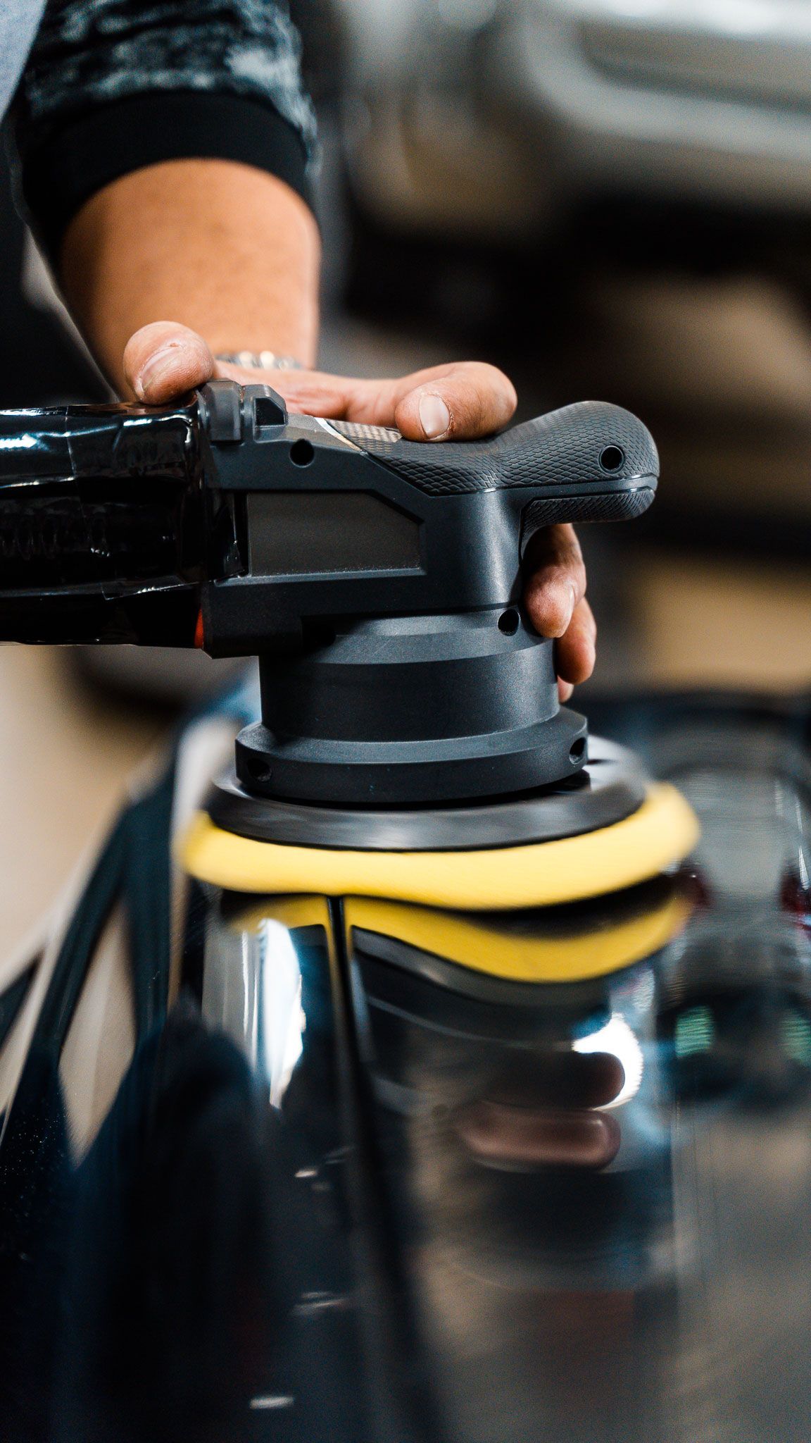 A person is polishing a car with a machine.