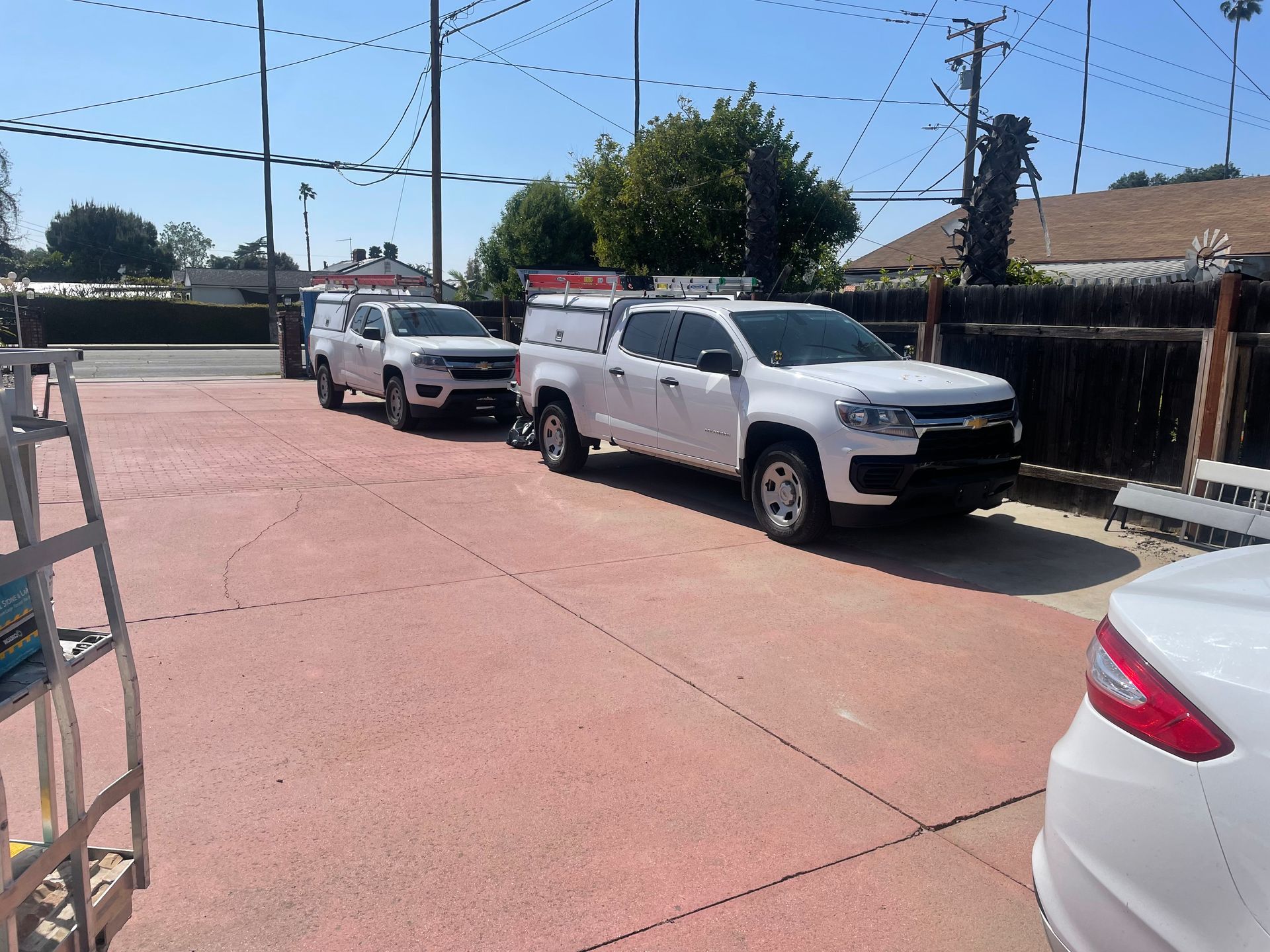 three white trucks are parked in a parking lot next to a white car
