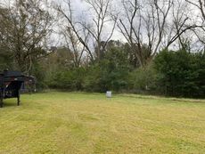 A trailer is parked in a grassy field with trees in the background.