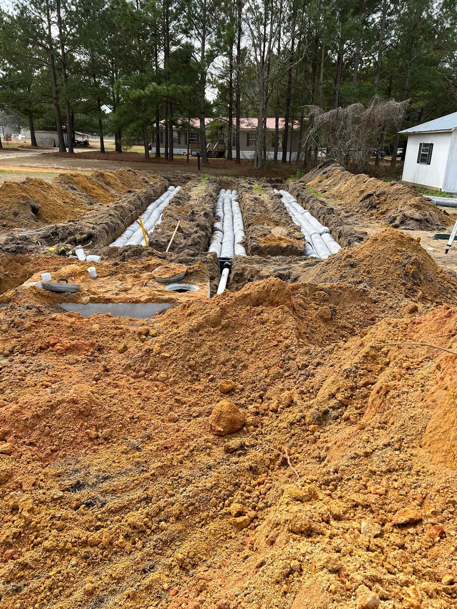 A pile of dirt is sitting in the middle of a field next to a house.