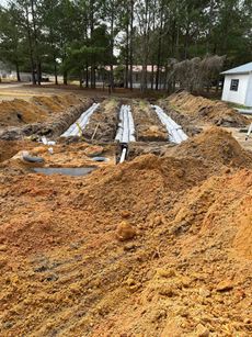 A pile of dirt is sitting in the middle of a field next to a house.